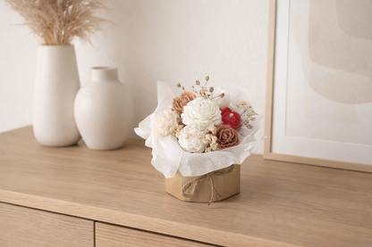 Blumenkerzenstrauß aus Rapswachs als Wohnraum-Dekoration auf einem hellen Sideboard im natürlichen Ambiente.